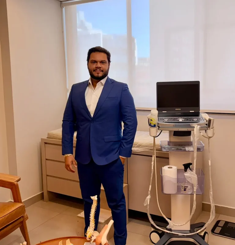 Dr. Leonardo Catizani no consultório, ao lado do aparelho de ultrassom usado nos procedimentos